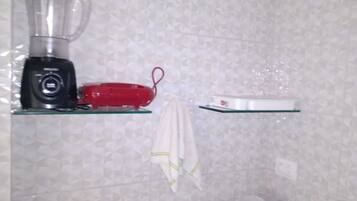 A kitchen with a blender, a red appliance, and a white scale on glass shelves.