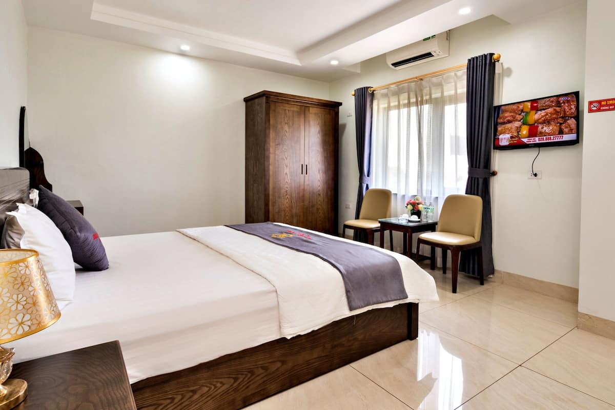 Habitación de hotel con cama, escritorio, silla, televisor y armario.