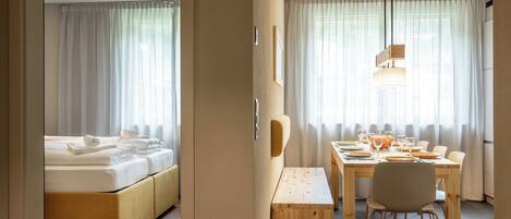 Una habitación de hotel con una cama, una mesa de comedor y un banco.