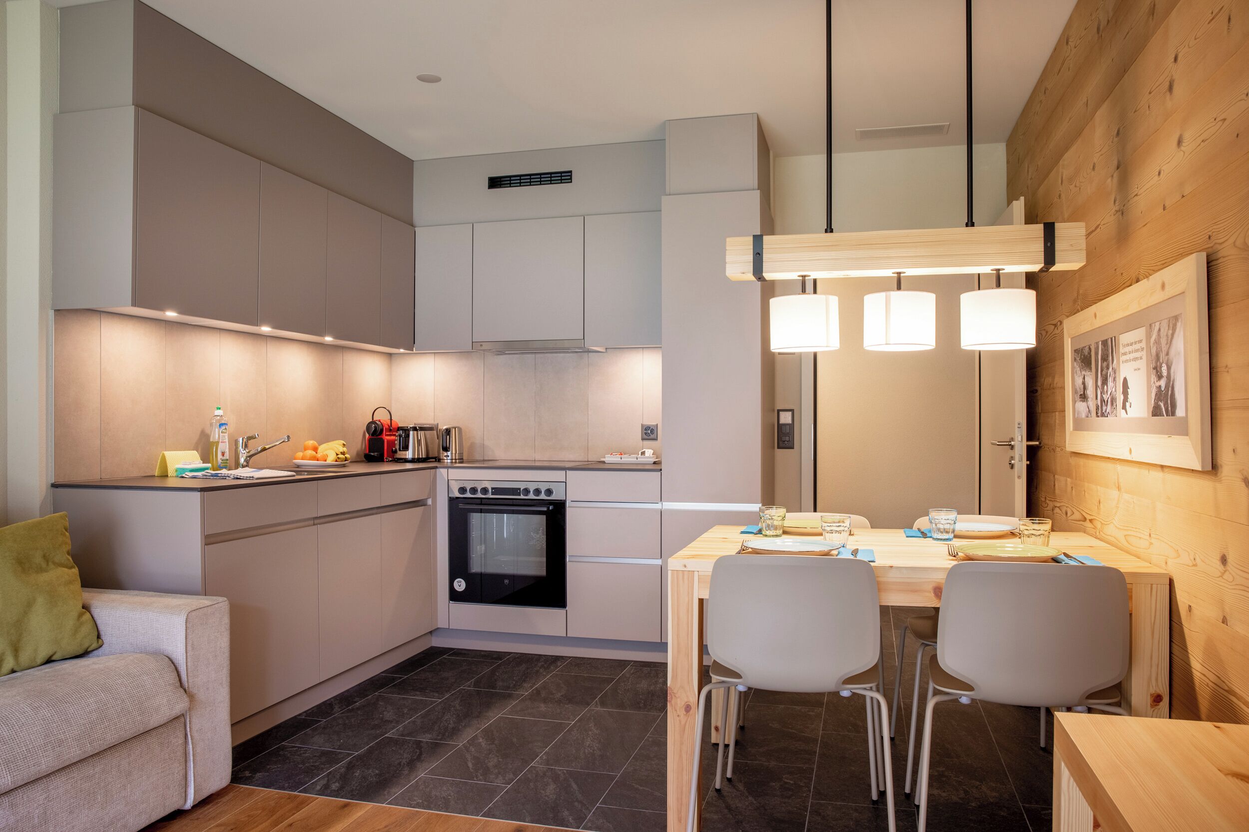 A modern kitchen with a dining area, built-in cabinets, a stove, and pendant lighting.