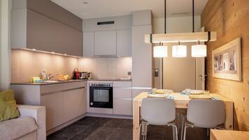 A modern kitchen with a dining area, built-in cabinets, a stove, and pendant lighting.