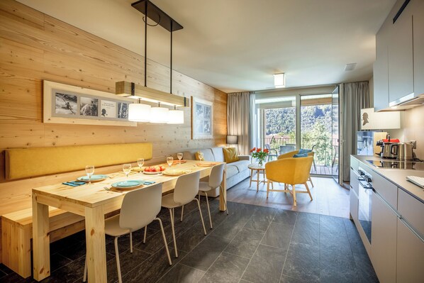 Eine moderne Küche mit Essbereich, Holzwänden und einem großen Fenster.