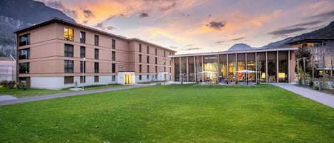Un hôtel moderne doté d’un toit plat, de nombreuses fenêtres et d’une pelouse bien entretenue.