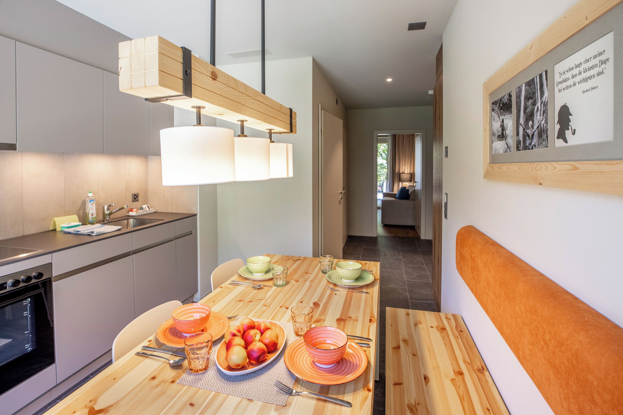 Una cocina moderna con una mesa de comedor preparada para cuatro personas, un horno empotrado y una estructura de techo de madera.