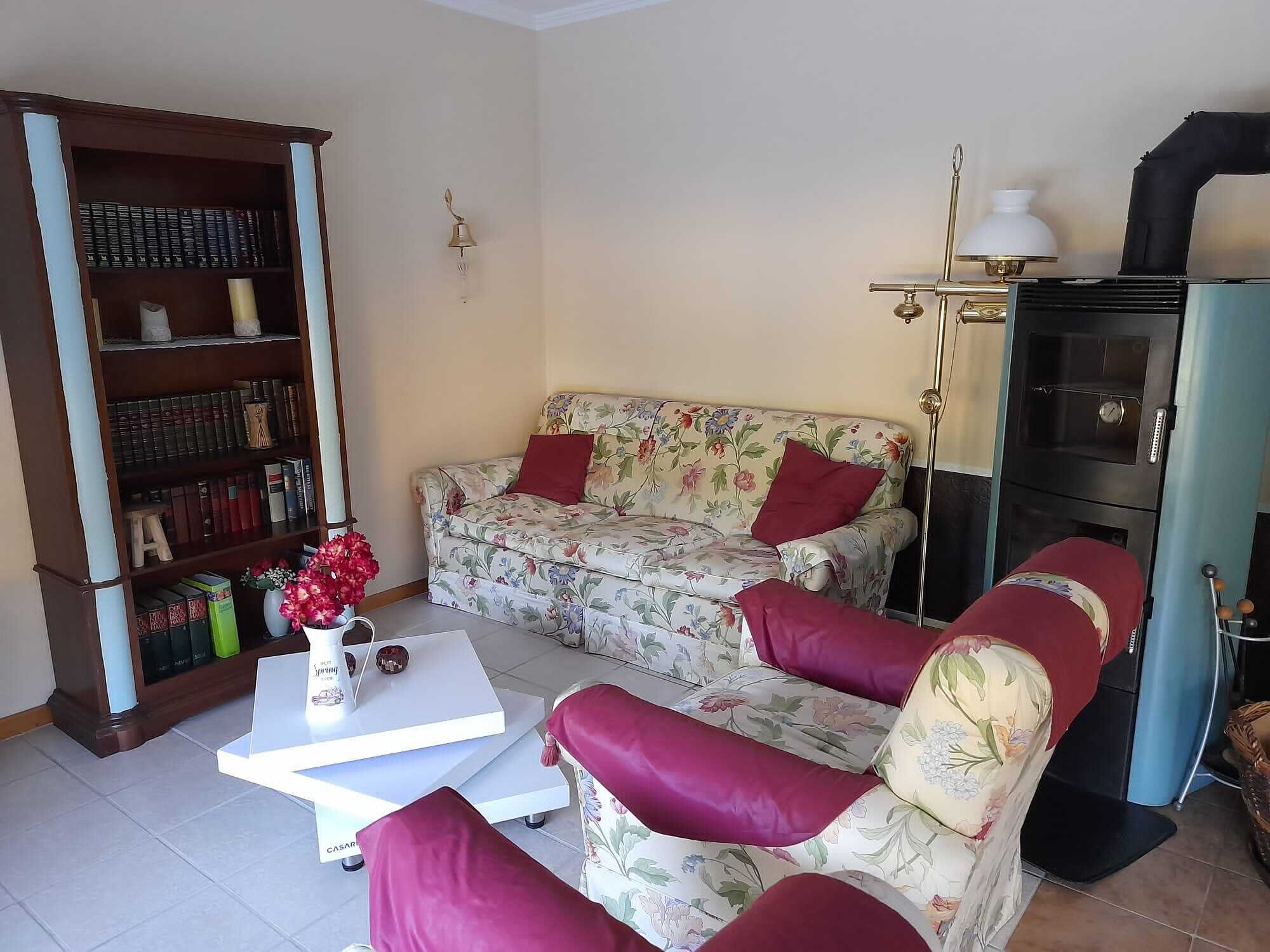 A living room with a sofa, armchairs, a coffee table, a bookshelf, and a decorative lamp.