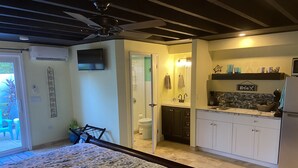 A bedroom with a bed, a bathroom with a toilet and sink, and a kitchen with cabinets and a refrigerator. - New listing! Easy walk to 3 separate Beaches, Pool, and multiple Restaurants! (St thomas)