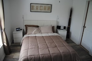Ein Schlafzimmer mit einem Bett, Nachttischen, einer digitalen Uhr und gerahmten Zertifikaten an der Wand.