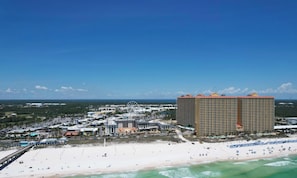 A coastal hotel with a beach view, a pier, and a Ferris wheel in the background.