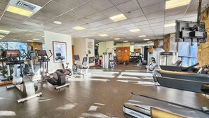 Ein Fitnessstudio mit Laufbändern, Crosstrainern und Gewichten.