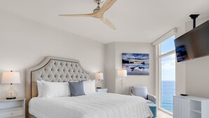 Een moderne slaapkamer met een groot bed, een plafondventilator, een televisie en uitzicht op de oceaan.