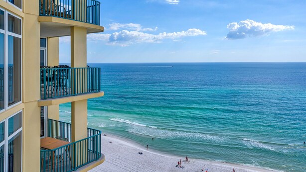 Een hotel met een balkon met uitzicht op een strand en de oceaan.