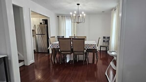 A dining area with a chandelier, wooden chairs, and a table set for four. - Short Walk to Metro - Fenced Yard + Covered Patio (Silver Spring)