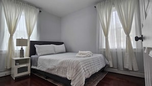 A bedroom with a bed, a nightstand, and sheer curtains. - Short Walk to Metro - Fenced Yard + Covered Patio (Silver Spring)