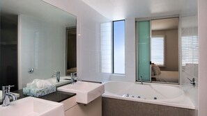Bathroom features a large mirror, two sinks, and a bathtub.