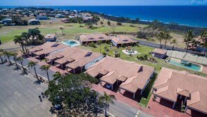 A residential area with multiple houses, a swimming pool, and a view of the ocean.