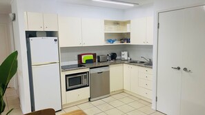 Compact kitchen area with oven, dishwasher, microwave, toaster, and coffee maker.