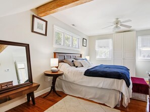 Relax in this serene bedroom with a large bed, ceiling fan, and large mirror.