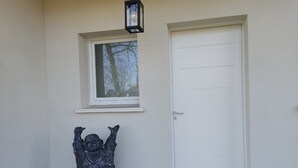 A statue of a figure with raised arms, a white door, and a window above the door. - Cottage Chaleureux Proche de L'océan (Grayan-et-l'Hôpital)
