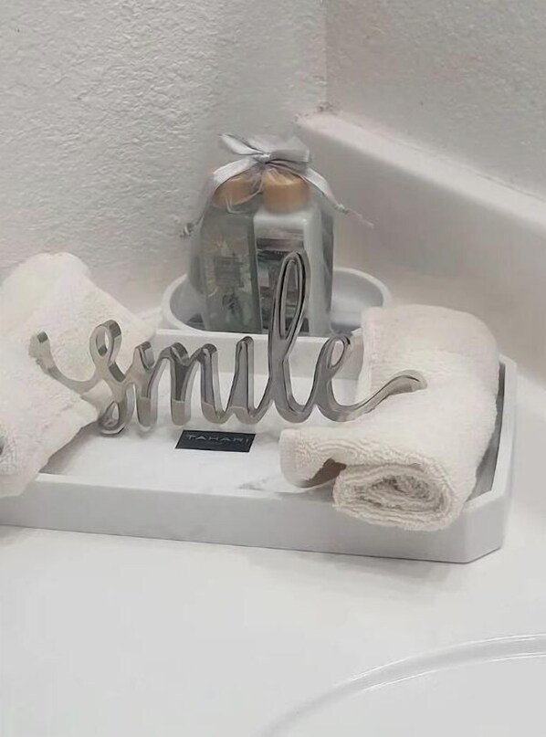 A bathroom sink with a towel rack holding two towels and a decorative sign that reads "smile". - Private Guesthouse Near Siesta Key & Downtown. (Sarasota)