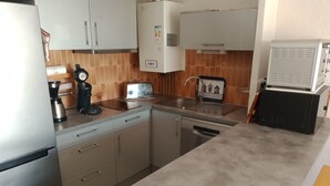 A compact kitchen with a refrigerator, a coffee maker, a toaster, and a dishwasher. - Seafront apartment, air-conditioned, walk-through, private pool, parking (Palavas-les-Flots)
