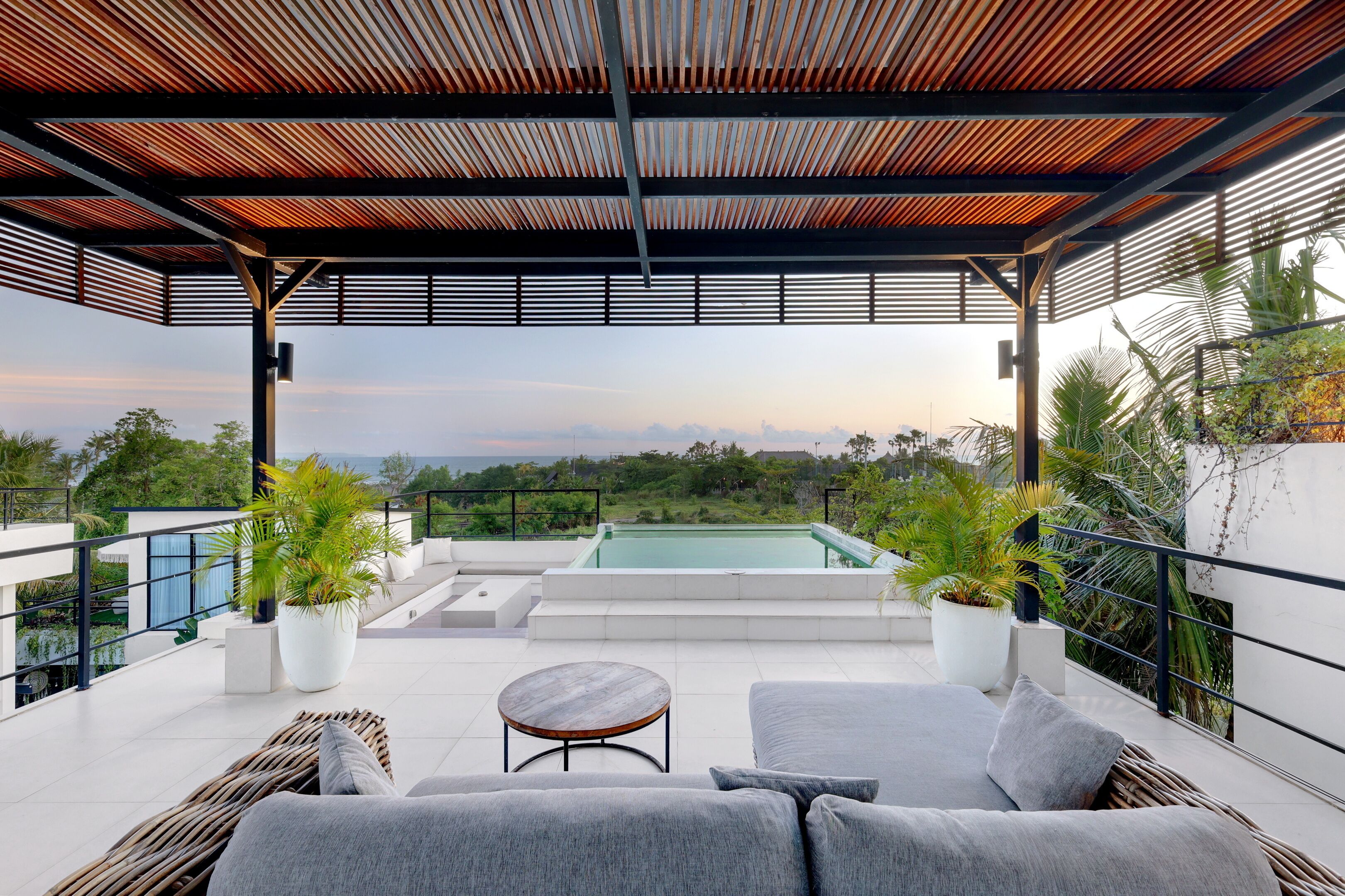 Une terrasse sur le toit avec une piscine, des sièges d’extérieur et des plantes en pot.
