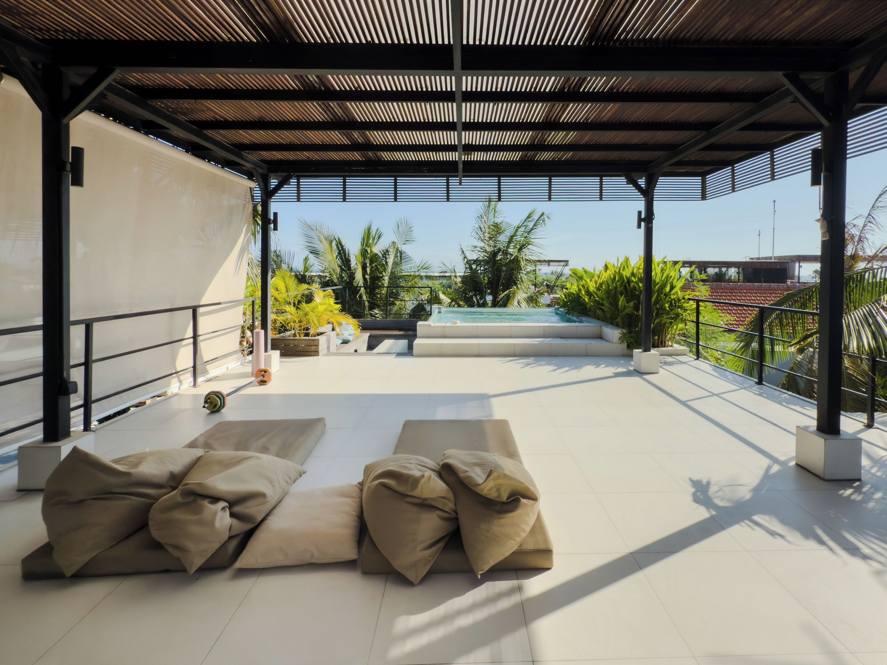 Un espace extérieur abrité, doté d’une piscine, de sièges confortables et offrant une vue sur le paysage environnant.