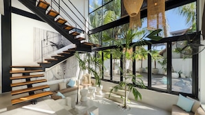Een modern interieur met een trap, zithoek en grote ramen.