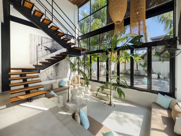 Een modern interieur met een trap, zithoek en grote ramen.