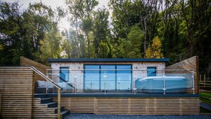Une structure moderne en bois, dotée d’une paroi vitrée, d’un escalier en bois et d’une petite piscine.