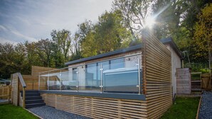 Une structure moderne en bois, dotée d’une paroi vitrée, d’un escalier et d’un chemin recouvert de gravier.