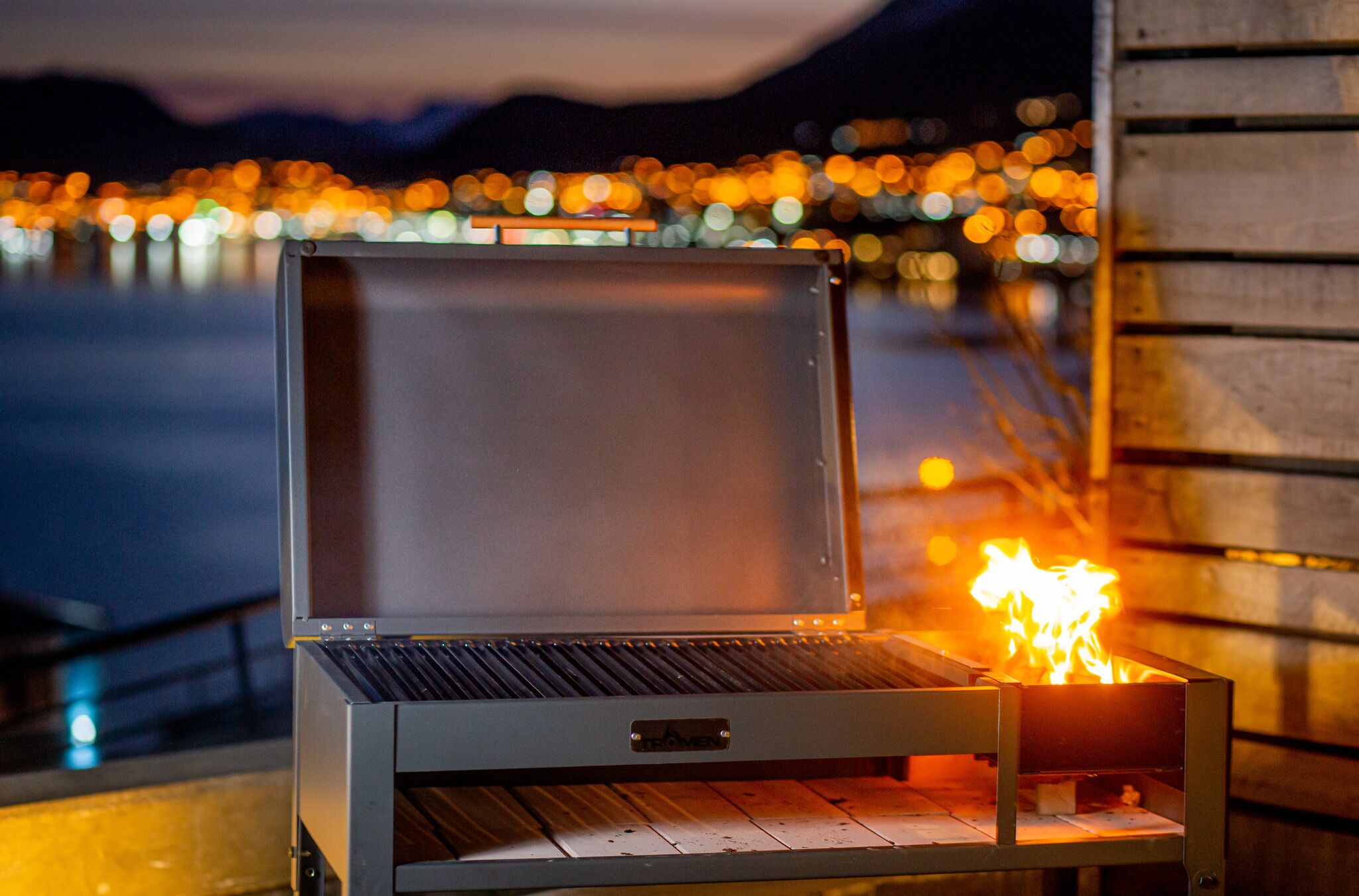Un barbecue d’extérieur doté d’un écran numérique, installé sur un fond nocturne illuminé par les lumières de la ville.