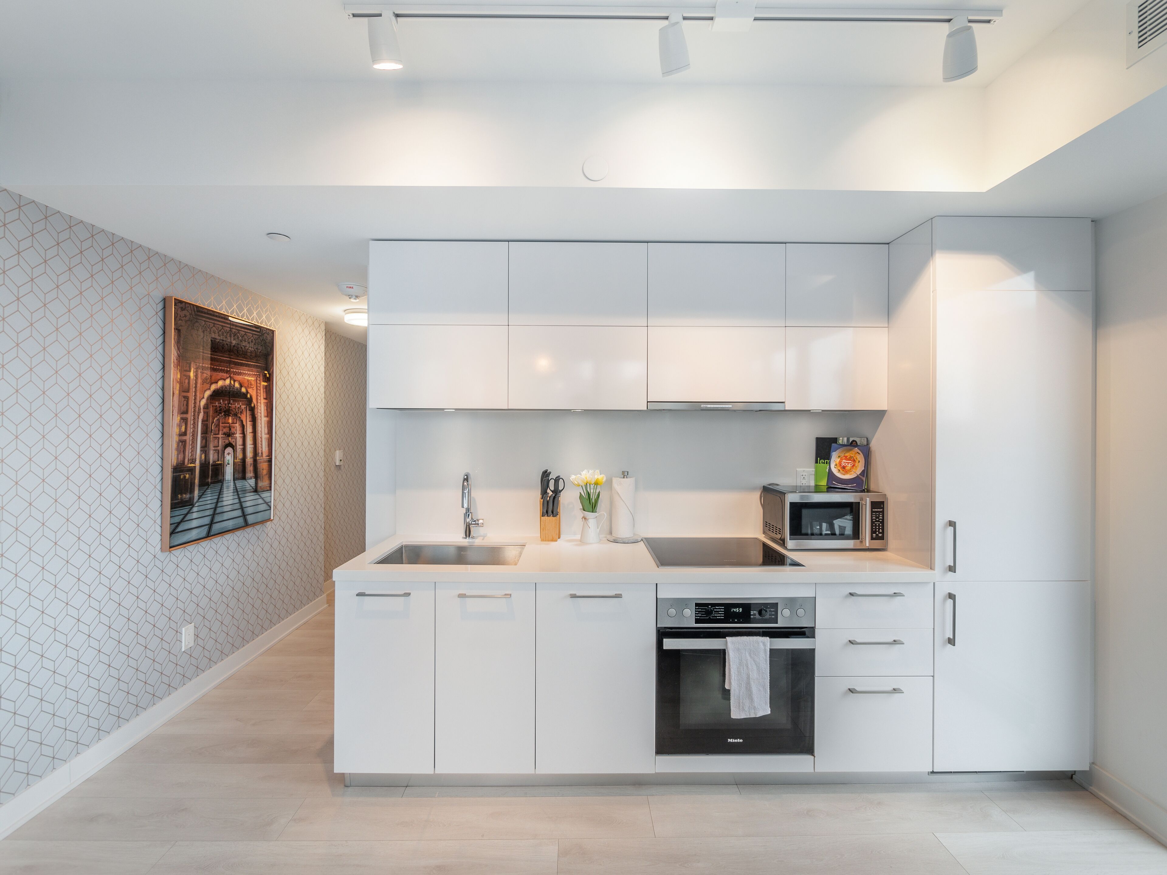A modern kitchen with white cabinetry, a built-in oven, and a microwave.