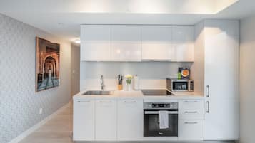 A modern kitchen with white cabinetry, a built-in oven, and a microwave.