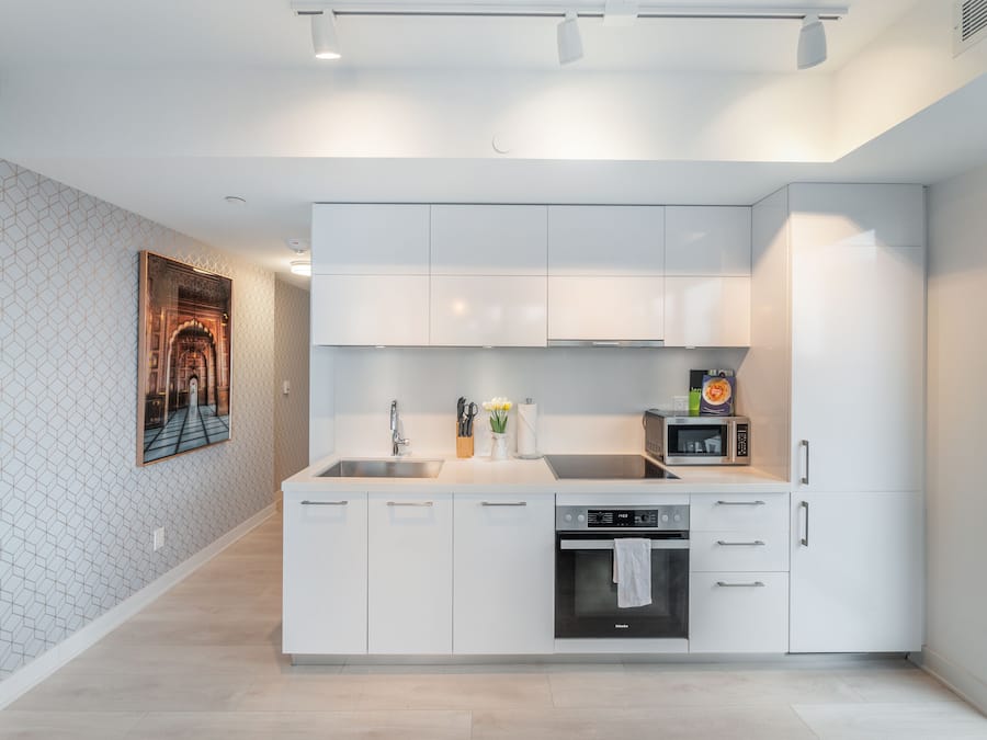 A modern kitchen with white cabinetry, a built-in oven, and a microwave.