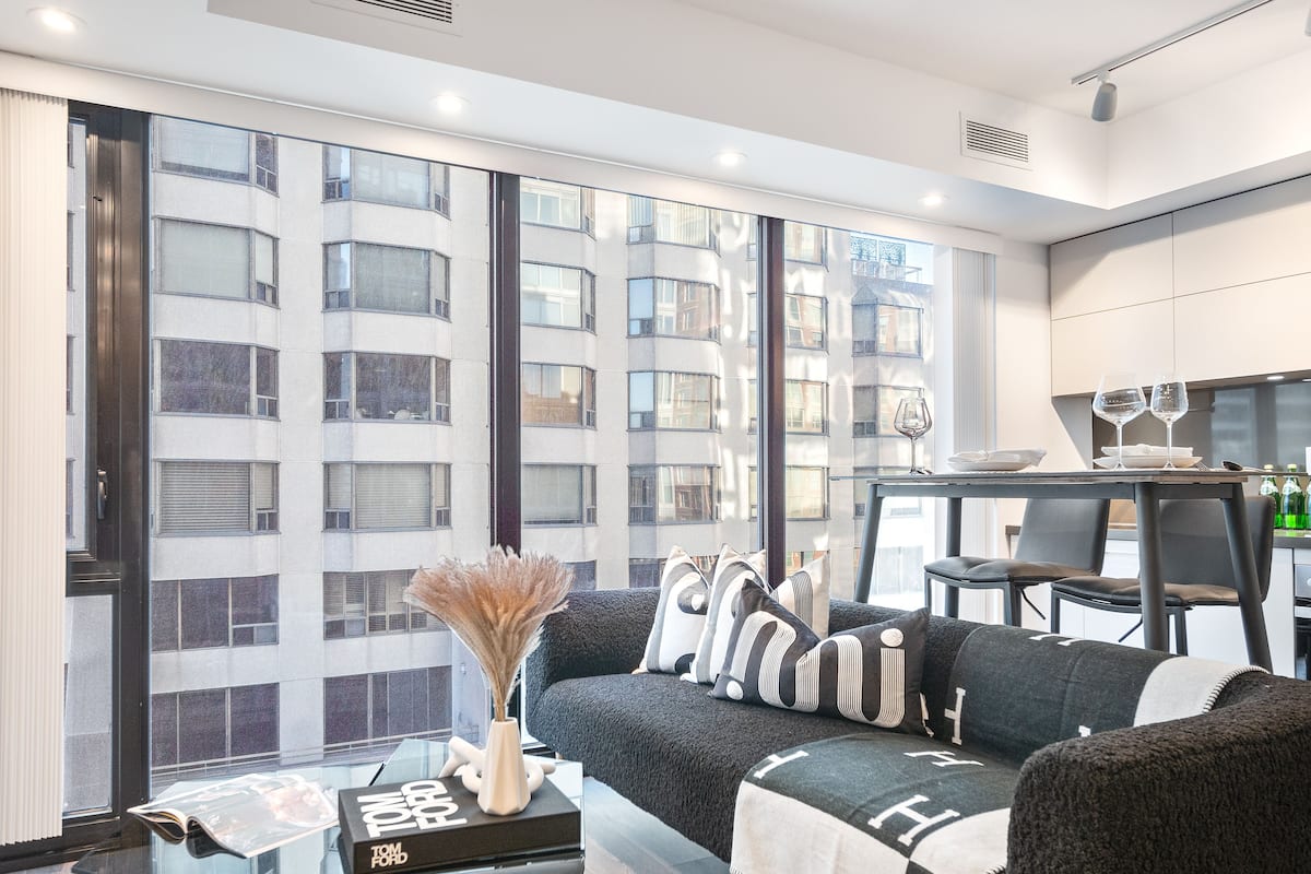 A modern living room with a sofa, a glass coffee table, and a dining area with a table and chairs.