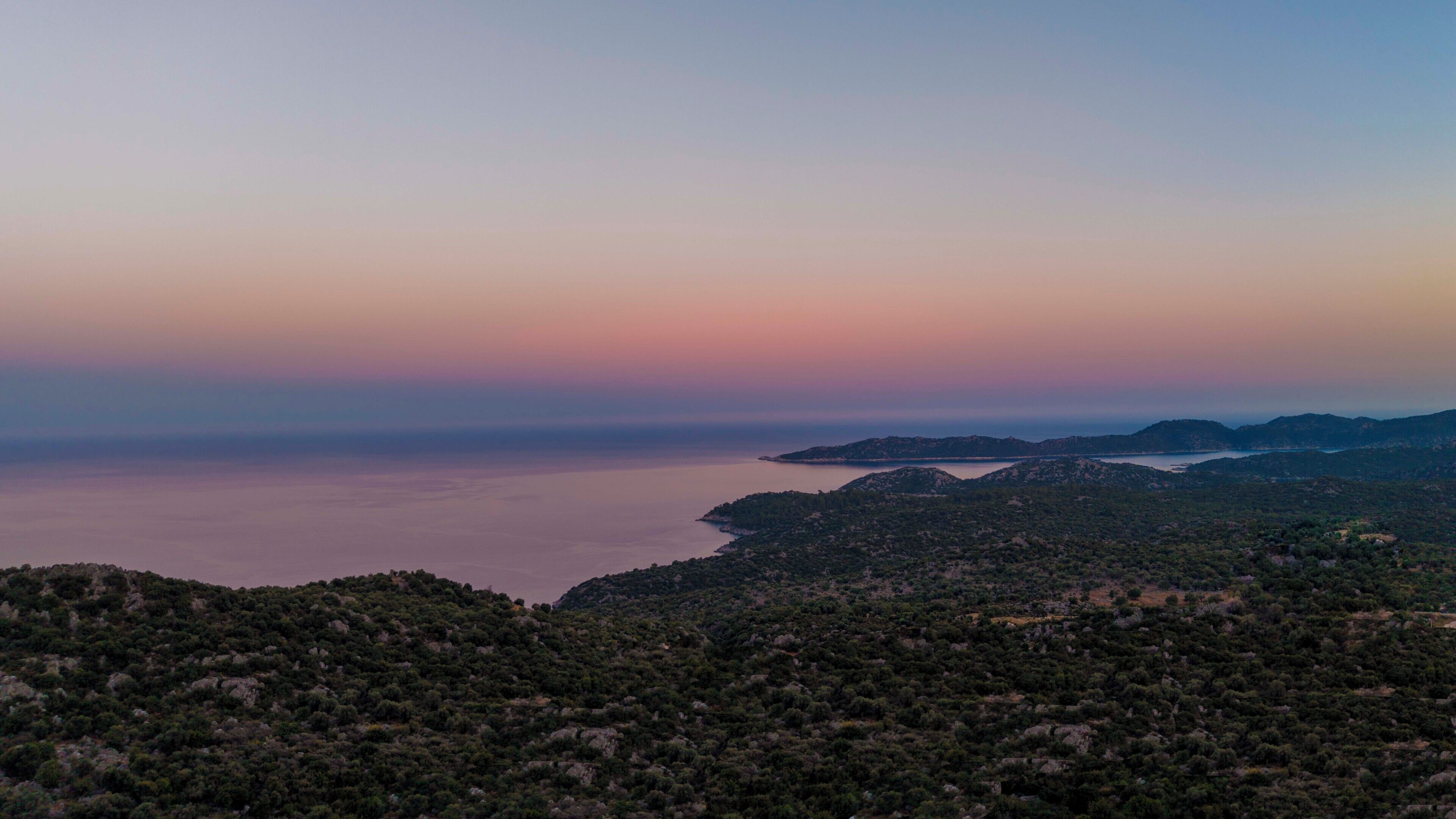 A coastal landscape with dense vegetation and a calm sea.