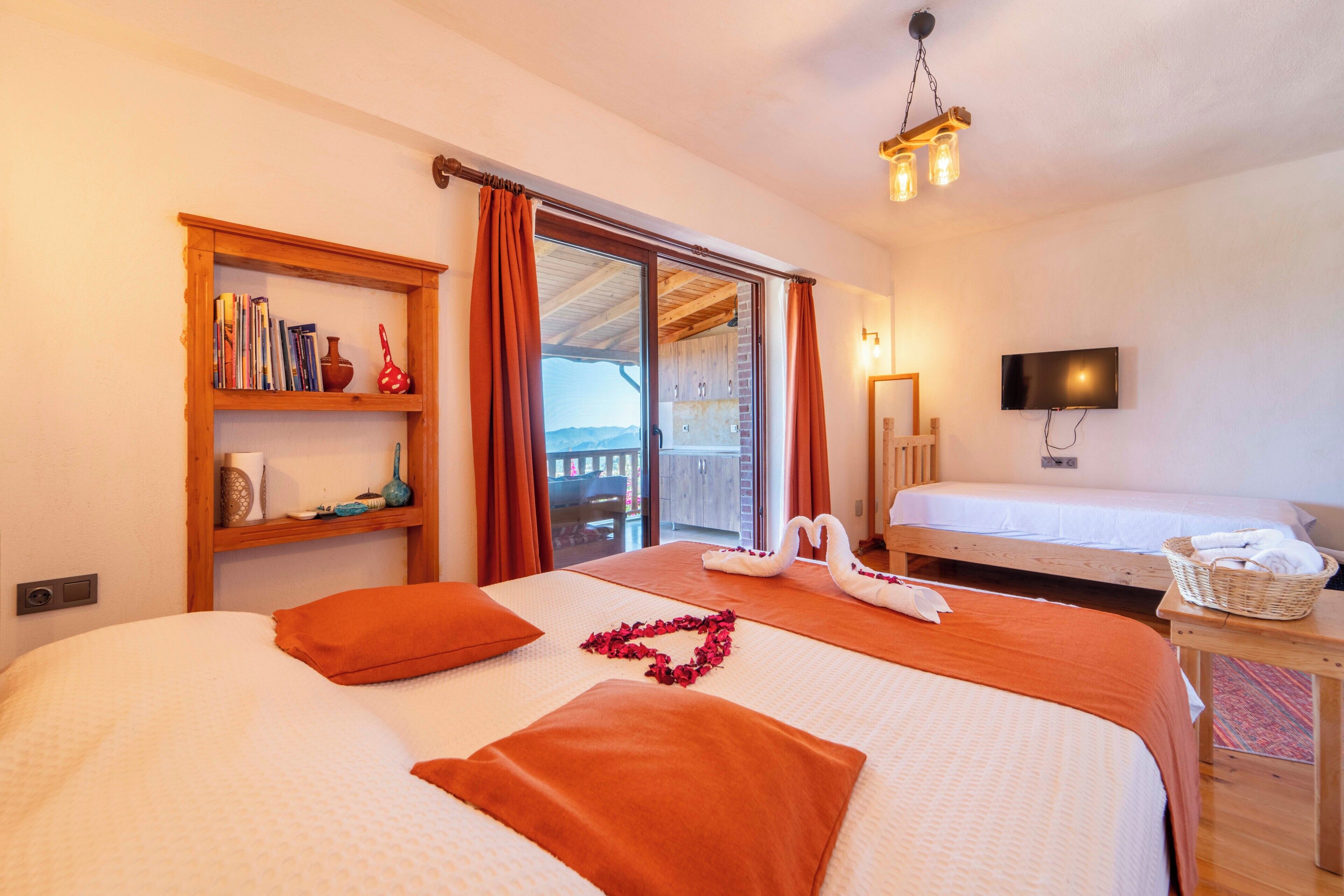 A hotel room with two beds, a bookshelf, a television, and a balcony with a view.