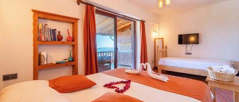 A hotel room with two beds, a bookshelf, a television, and a balcony with a view.