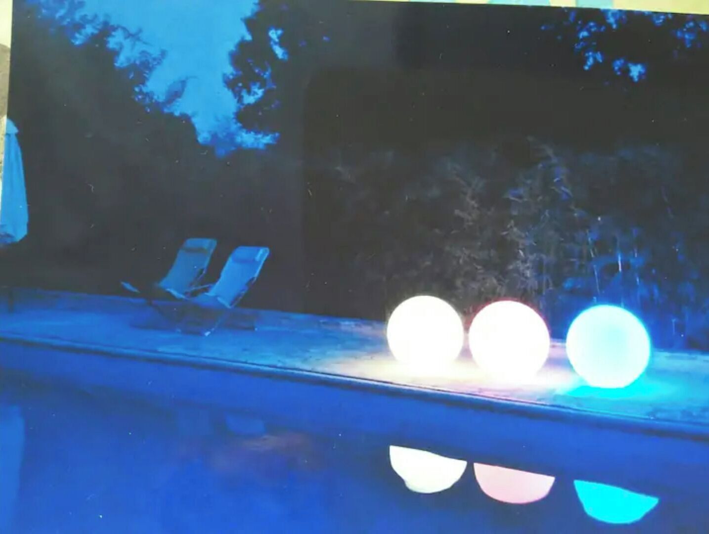 Ein Pool mit Liegestühlen und Spiegelungen von Lichtern.