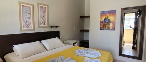 Ein Hotelzimmer mit einem Bett, einem Nachttisch, einem Gemälde und einer Tür zu einem anderen Raum.