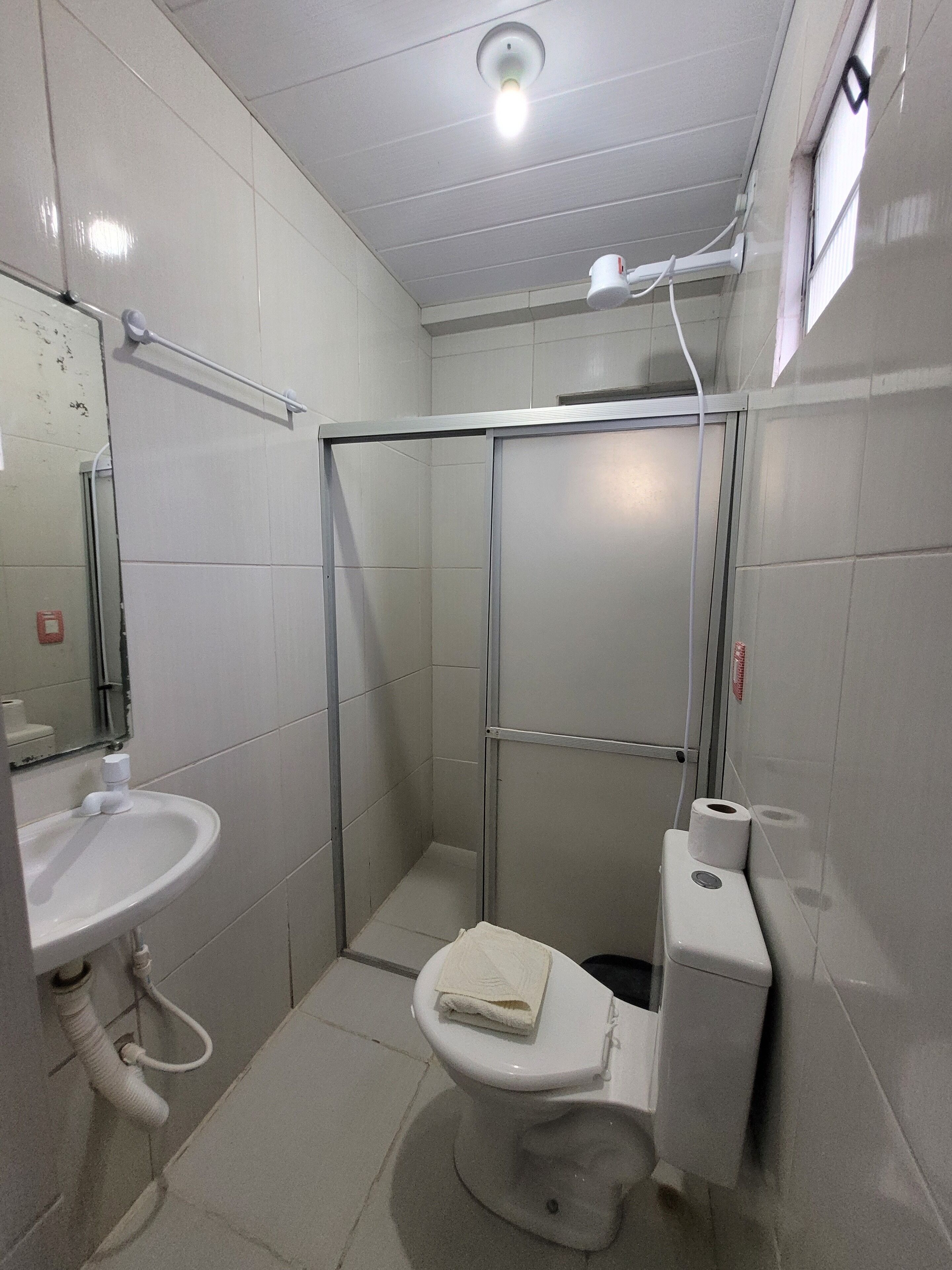 Een kleine, praktische badkamer met een wit wastafel, toilet en douchecabine.