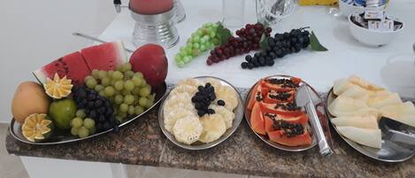 Una bandeja de frutas con diversas frutas y una licuadora sobre una encimera de cocina.