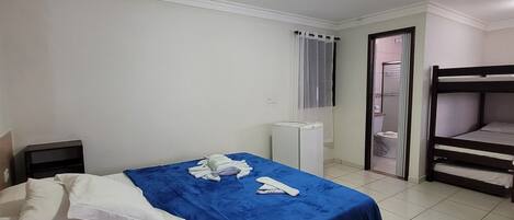 Ein Hotelzimmer mit Bett, Nachttisch, Schreibtisch, Stuhl, Kleiderschrank und einem Schlafplatz.