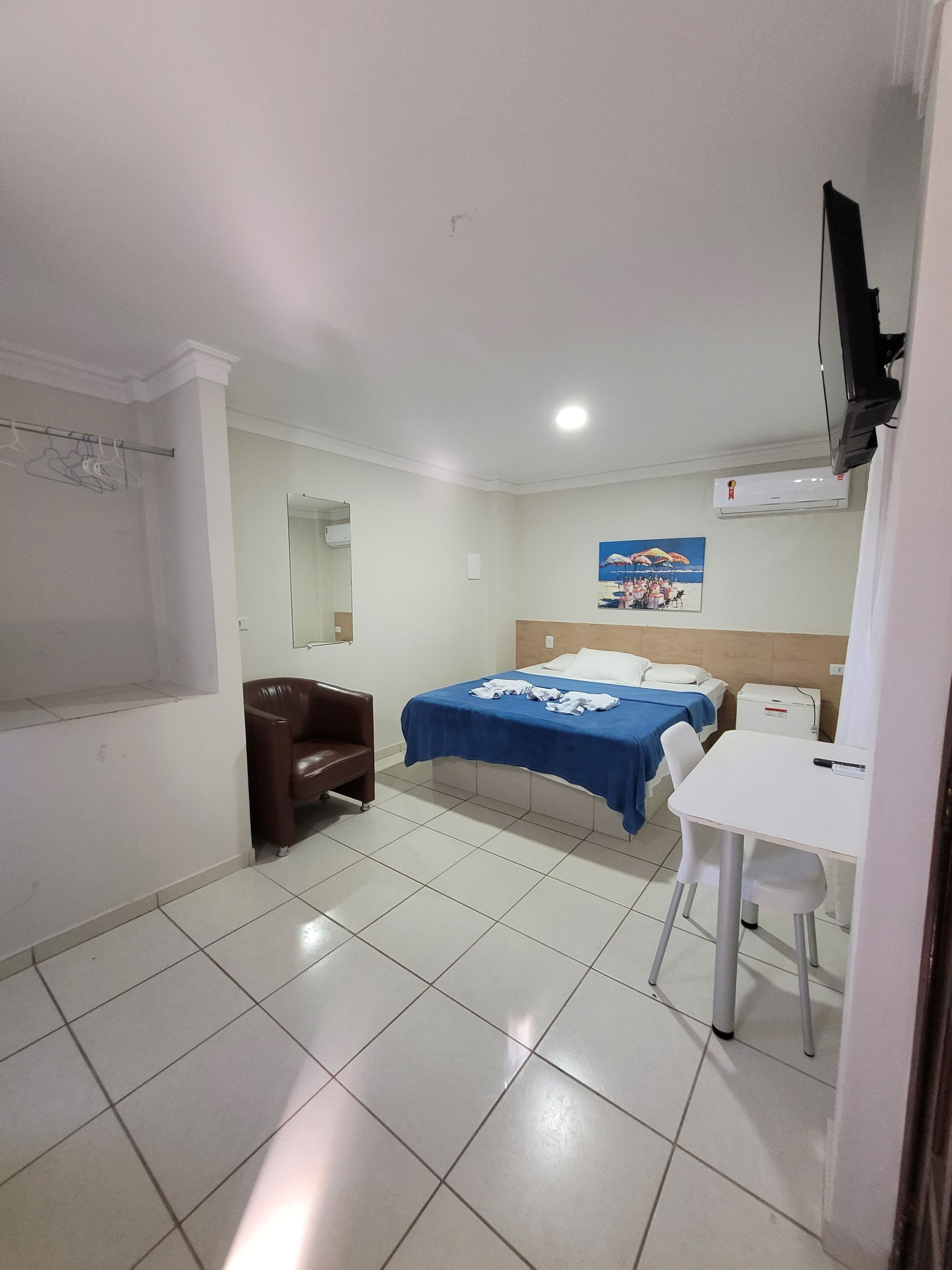 Habitació d'hotel amb llit, escriptori, cadira, televisió i armari.