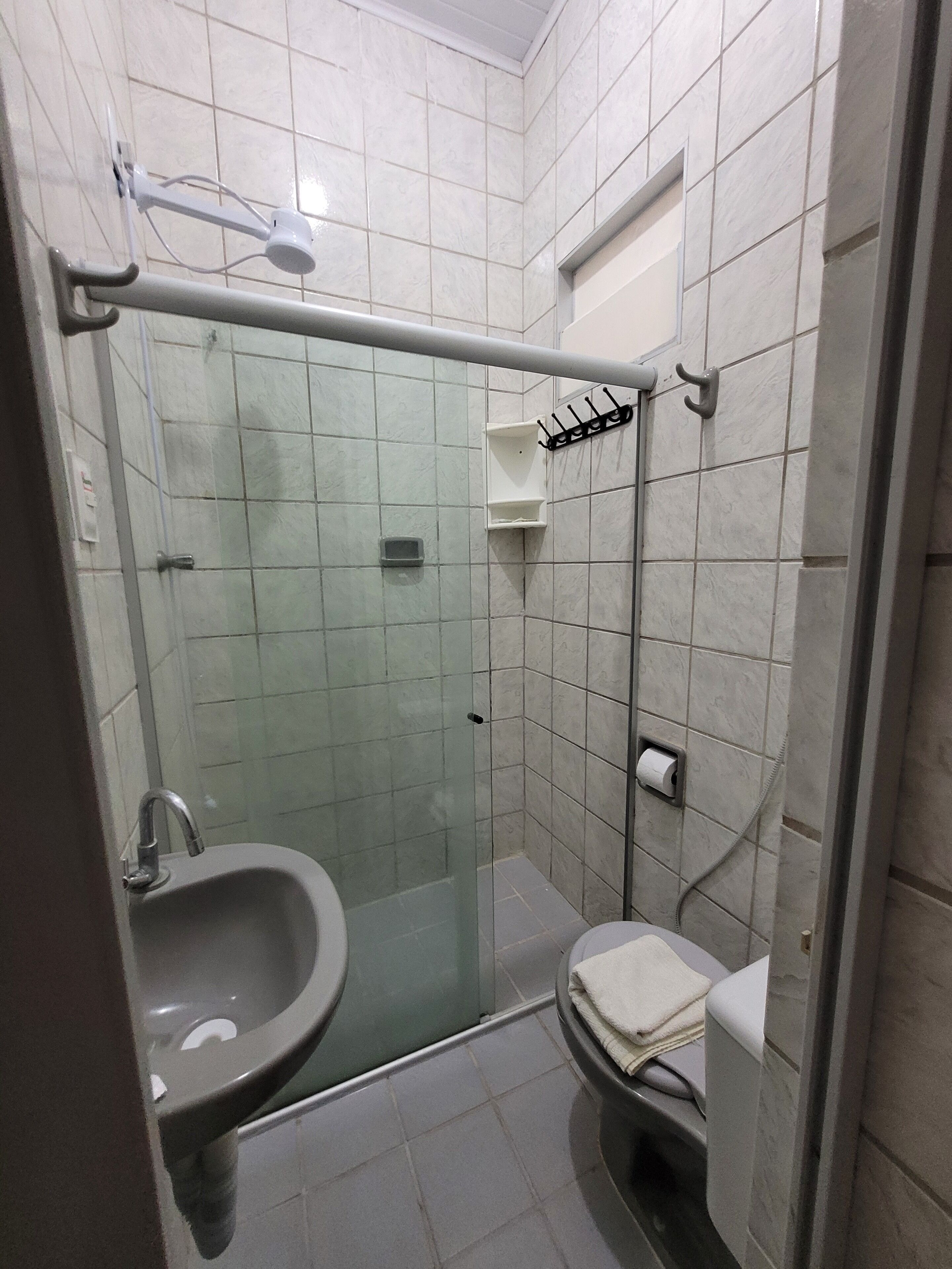 Un baño pequeño y moderno con ducha envuelta en vidrio, un lavamanos y un inodoro.