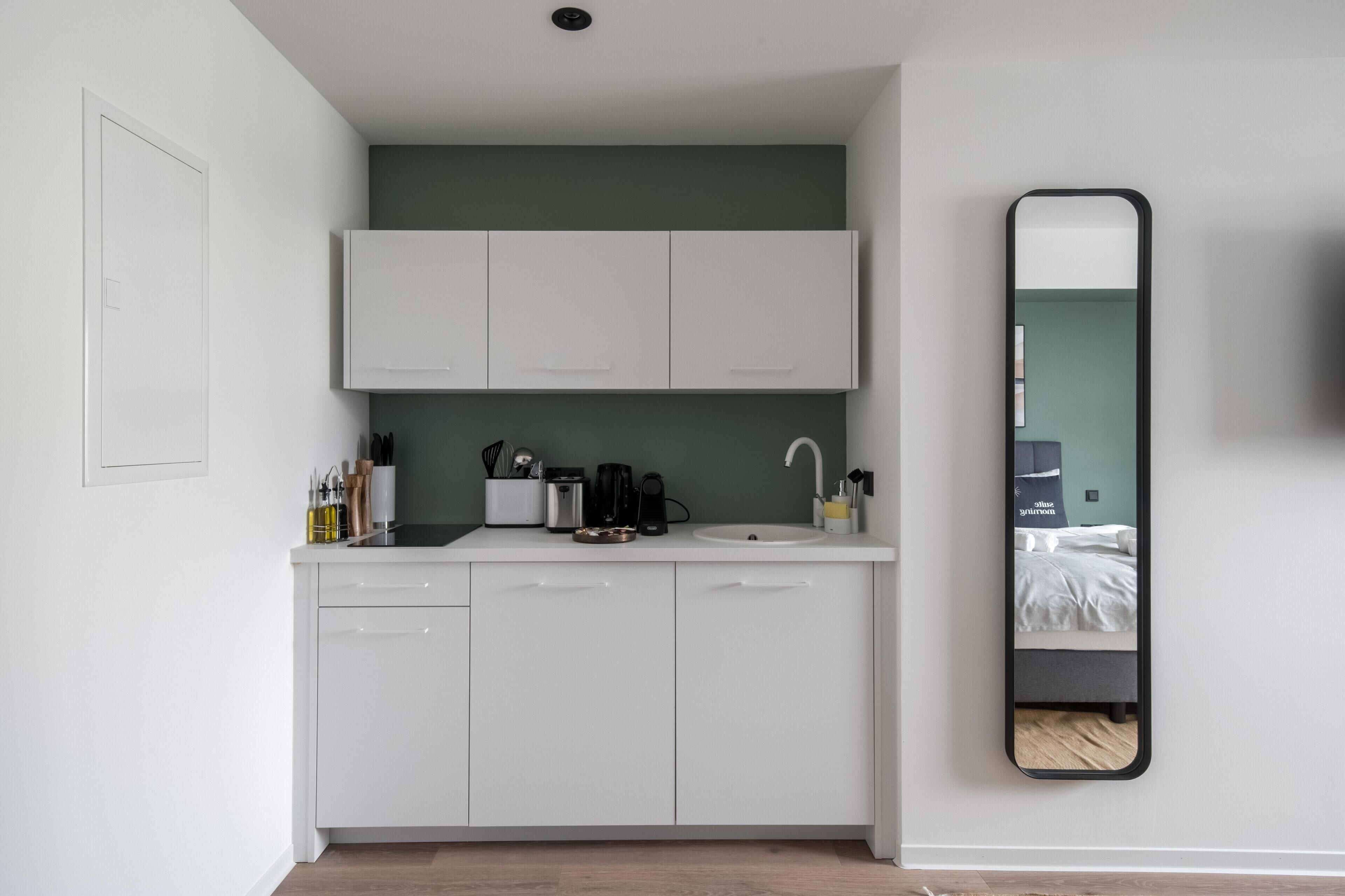 A compact kitchen with white cabinets, a sink, and a coffee maker.