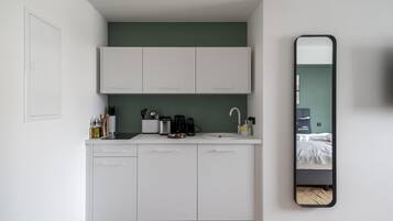 A compact kitchen with white cabinets, a sink, and a coffee maker.
