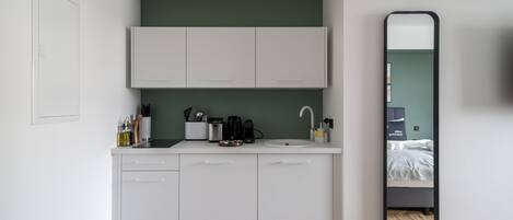A compact kitchen with white cabinets, a sink, and a coffee maker.