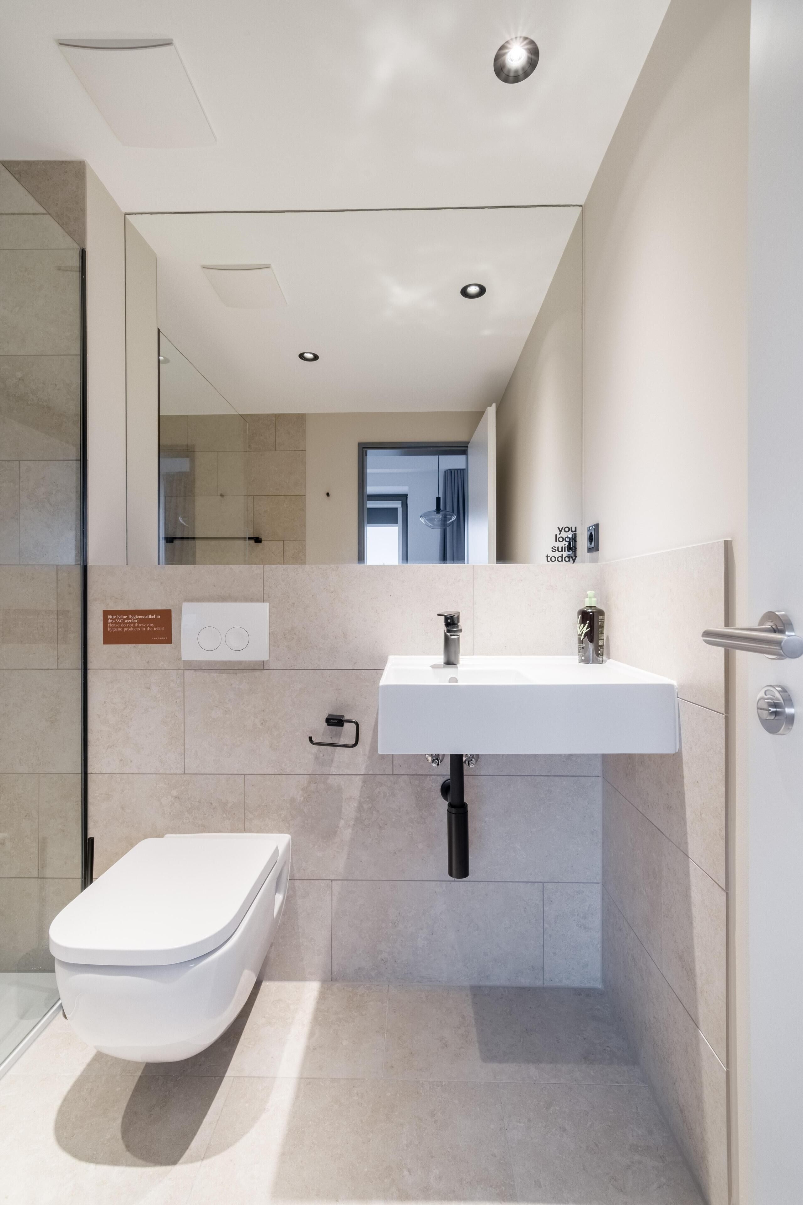 A modern bathroom with a toilet, sink, and shower.