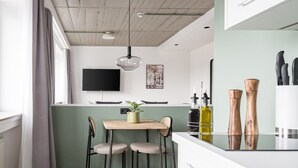 A modern kitchen with a wooden dining table, two chairs, and a hanging light fixture. - Limehome Saarbrücken Berliner Promenade (Saarbrücken)